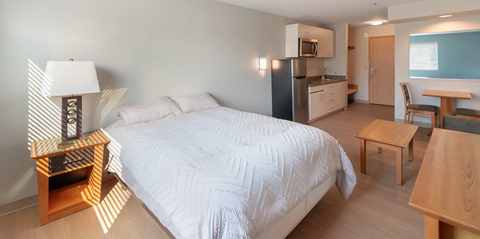 A bedroom with a bed, a table, and a chair.